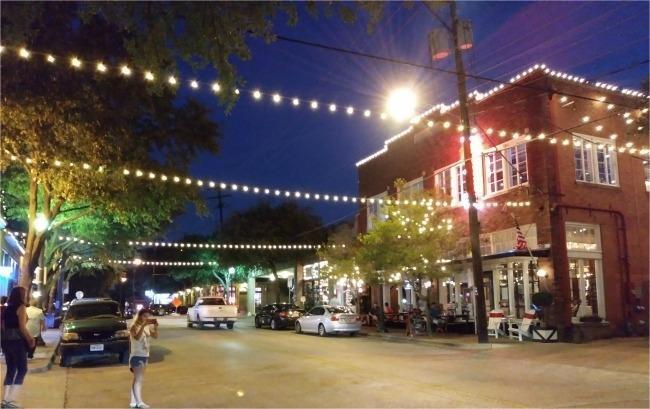 The charming storefronts and pedestrian-friendly streets of the Bishop Arts District at night, a popular hidden gem attraction for visitors near Azle.