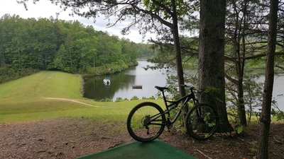 A mountain bike leaning against a tree overlooking the scenic waters of Eagle Mountain Lake, highlighting outdoor attractions near Azle.
